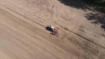 aerial view as a farmer on an old blue tractor sows a field with corn video