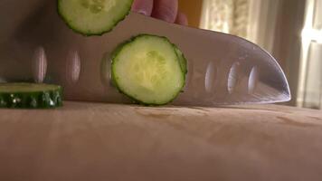 pov kitchen knife cuts fresh cucumber on wooden kitchen cutting board video