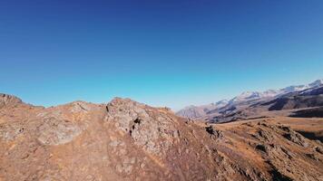 dyka från de topp av en klippig berg ner under de rocks. sport fpv Drönare flygande över klippig berg backe. hisnande antal fot av en dynamisk falla från en klippa video