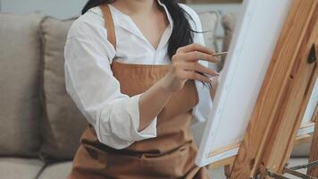 Over the shoulder selective focus shot of male artist using brush while adding color paint to pencil drawing on canvas video