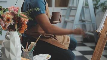 over- de schouder selectief focus schot van mannetje artiest gebruik makend van borstel terwijl toevoegen kleur verf naar potlood tekening Aan canvas video