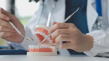 Dentist sitting at table with jaw samples tooth model and working with tablet and laptop in dental office professional dental clinic. medical doctor working video