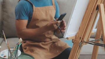 plus de le épaule sélectif concentrer coup de Masculin artiste en utilisant brosse tandis que ajouter Couleur peindre à crayon dessin sur Toile video