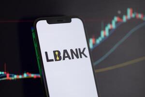 KYIV, UKRAINE - MARCH 15, 2024 Lbank logo on iPhone display screen and crypto currency value charts photo