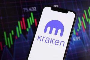 KYIV, UKRAINE - MARCH 15, 2024 Kraken logo on iPhone display screen and crypto currency value charts photo