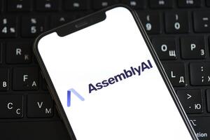 KYIV, UKRAINE - MARCH 17, 2024 AssemblyAI logo on iPhone display screen and MacBook keyboard photo