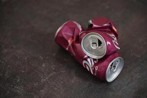 KYIV, UKRAINE - 4 MAY, 2023 Coca cola soft drink crumpled tin can with cherry flavour photo