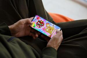 Candy Crush Saga mobile iOS game on iPhone 15 smartphone screen in male hands during mobile gameplay photo