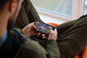 Lineage M mobile iOS game on iPhone 15 smartphone screen in male hands during mobile gameplay photo