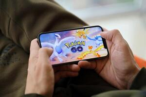 pokemon Vamos móvil ios juego en iphone 15 teléfono inteligente pantalla en masculino manos durante móvil Como se Juega foto