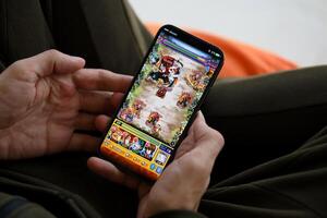 Monster Strike mobile iOS game on iPhone 15 smartphone screen in male hands during mobile gameplay photo