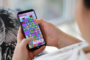 Candy Crush Saga mobile iOS game on iPhone 15 smartphone screen in female hands during mobile gameplay photo