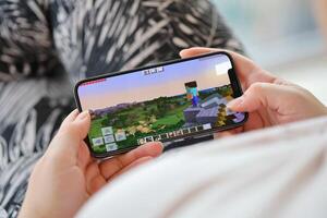 Minecraft mobile iOS game on iPhone 15 smartphone screen in female hands during mobile gameplay photo