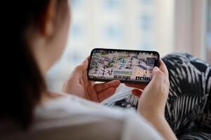 Lineage M mobile iOS game on iPhone 15 smartphone screen in female hands during mobile gameplay photo