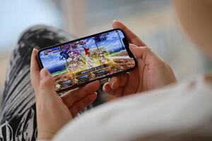Fate Grand Order mobile iOS game on iPhone 15 smartphone screen in female hands during mobile gameplay photo