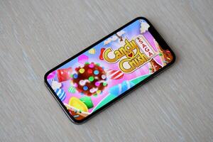 Candy Crush Saga mobile iOS game on iPhone 15 smartphone screen on wooden table during mobile gameplay photo