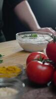 Chef adds pieces of fresh greens to the ranch dressing. Ripe, bright vegetables are spread out on the kitchen counter. Vertical. Close up. 4k. video