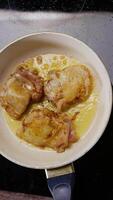 Juicy chicken breast, seasoned with curry, is fried in boiling oil in a white frying pan for cooking. top view. Vertical. Close up. 4k. Top view video