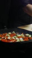 chef throws sliced zucchini and other vegetables into a pan to cook a vegetable stew. Vertical. Close up. 4k. High angle video