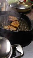 Chef is stirring the chicken in a wok in the kitchen of an upscale restaurant, against the backdrop of a steaming pot and the ingredients for the dish. Vertical. Close up. 4k. High angle video