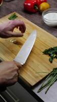 chef presses le Ail avec une couteau et alors, avec professionnel compétence et dextérité, coupes il dans petit pièces à ajouter à le blanc sauce. vertical. proche en haut. 4k. haute angle video