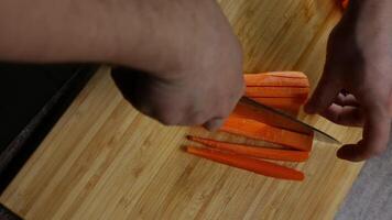 Cook expertly cuts carrots on a cutting board as the camera pans around. Top view . Close up. 4k. video