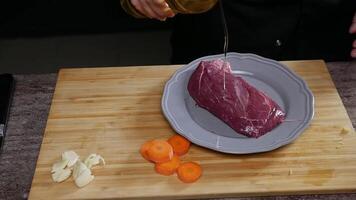 cuisinier volonté préparer le steak. cuisinier verse légume pétrole sur une juteux, rouge et appétissant pièce de du boeuf et puis se tourne il sur. proche en haut. lent mouvement. haute angle. video