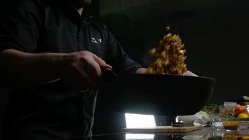 cocinero lanzamientos el vegetales dentro el aire y papas fritas ellos en un cacerola. él mezclas ellos continuamente a evitar ellos desde incendio. remover freír. medio disparo. 4k video