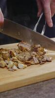 Juicy, steaming chicken meat, freshly cooked, is sliced onto a cutting board using a large knife. The golden-crusted meat oozes with appetizing fat. Vertical. Close up. 4k. High angle video