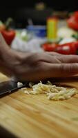 chef deftly slices garlic into salad slices with a large kitchen knife on a cutting board. Vertical. Close up. 4k. video