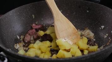 The cook combines potatoes with meat to create a dish of simple, rustic cuisine. Close up. Slow motion. High angle. video