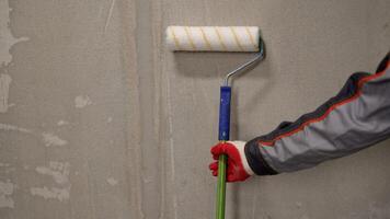 Roller with a long handle for painting walls and floors. The worker holds a roller in his hand. A man is holding a roller for painting walls. photo