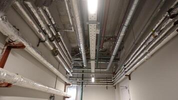 Pipes, ventilation and air conditioning in an underground garage. New house. Pipes in the basement of a new house. New metal pipes in the basement of a residential building. photo