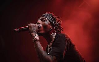 A African American singer of performer singing on stage, illuminated by dramatic red lighting amidst smoke. photo