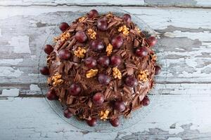 Cake with chocolate icing and grapes on a rustic background photo