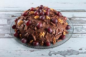 Cake with chocolate icing and grapes on a rustic background photo