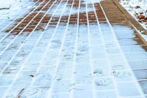 Paving paths in the park, covered with the first snow in winter. photo