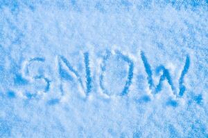 The word snow written on the snow. Winter and cold weather concept. photo