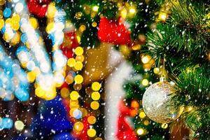 Christmas balls, toys and glowing garlands on an artificial spruce with falling snow. photo