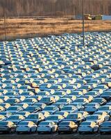 Volkswagen Group Rus, Russia, Kaluga - NOVEMBER 17, 2020 Rows of a new cars parked in a distribution center on a sunny autumn morning and a car factory buildings. photo