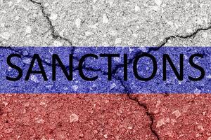 The flag of the Russian Federation on a cracked concrete wall with the words SANCTIONS. Concept photo