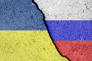 The crack between the Russian Federation and Ukrainian flags on the concrete wall. The concept of sanctions, conflict and war. photo