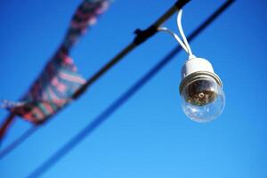 equipado y eléctrico con ligero bombillas es colgando en el viento y luz de sol en azul cielo foto