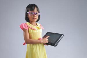 an indonesian 10 years old little girl wearing glasses pointing a gadget screen photo