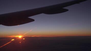 Visão a partir de a avião janela do a asa, nuvens e uma lindo pôr do sol. video