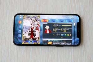 Fate Grand Order mobile iOS game on iPhone 15 smartphone screen on wooden table during mobile gameplay photo