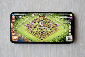 Clash of Clans mobile iOS game on iPhone 15 smartphone screen on wooden table during mobile gameplay photo