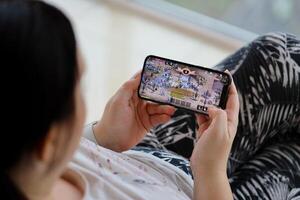 Lineage M mobile iOS game on iPhone 15 smartphone screen in female hands during mobile gameplay photo