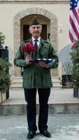 Amerikaans leger veteraan wacht buiten huis met bloemen en vlag video