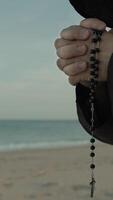 Religious Hands Of A Monk Praying Rosary On The Beach video